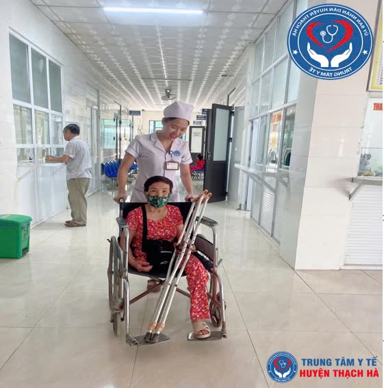 Viên chức y tế tận tình đẩy xe lăn đưa người bệnh cao tuổi đến phòng khám